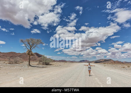 Jeune fille qui marche sur la route de gravier désert de Namibie. Banque D'Images