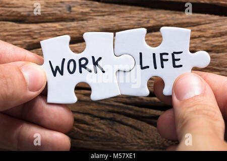 Closeup of hands holding work life matching puzzle pieces contre le bois Banque D'Images