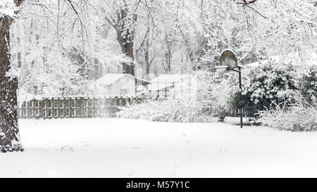 Panneau de basket-ball couvert de neige dans le jardin avec clôture et shack dans l'arrière-plan Banque D'Images