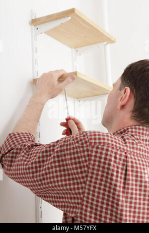 L'homme l'installation d'étagères en bois sur les supports Banque D'Images