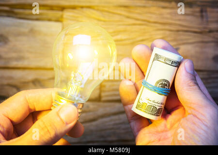 Closeup of hands holding dollars et ampoule allumée Banque D'Images