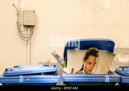 Un Tomb Raider Angelina Jolie stand-up jonché d'affichage dans un bac bleu grabage. Banque D'Images