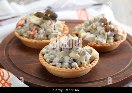 Tartelettes avec salade russe sur une planche à découper en bois Banque D'Images