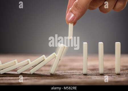 Portrait of businessman picking pièce relevant domino sur table en bois Banque D'Images