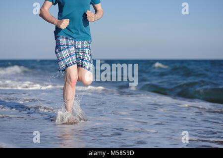 Barefoot man pendant le jogging sur une plage Banque D'Images