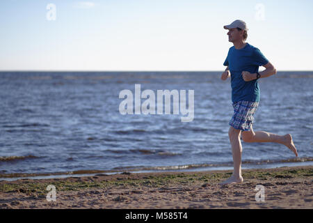 Barefoot man pendant le jogging sur une plage Banque D'Images