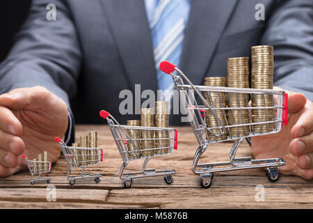 Portrait of businessman couvrant les pièces dans des chariots à table en bois Banque D'Images