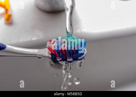 Brosse à dents avec du dentifrice et l'eau du robinet Banque D'Images