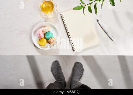 Style minimal de mise à plat de l'ordinateur portable ouvert avec table, croissant et thé. Banque D'Images