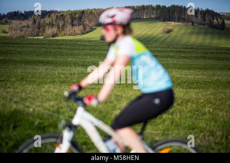 Vélo de montagne femelle non mise au point avec l'accent en paysage dans la distance derrière elle Banque D'Images