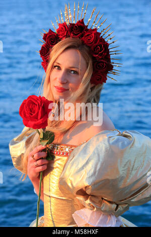 Une belle jeune fille avec un diadème fait de roses rouges pendant le Carnaval de Venise (Carnevale di Venezia) à Venise, Italie Banque D'Images