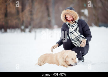 Photo de femme accroupie à côté de labrador dans winter park Banque D'Images