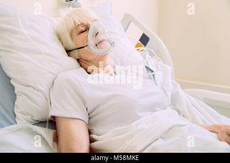 Femme âgée avec masque à oxygène, couché dans un lit d'hôpital Banque D'Images