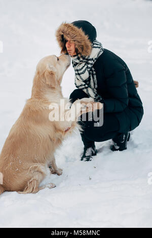 Photo de labrador patte donnant à la fille en veste noire sur journée d'hiver Banque D'Images