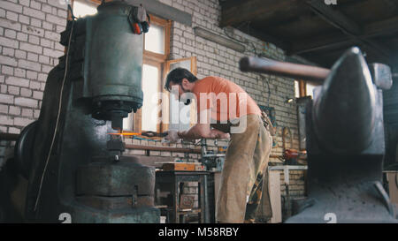 Homme forgeron forge le métal au marteau mécanique Banque D'Images
