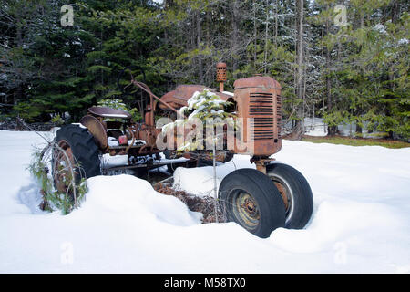 Un vieux tracteur FARMALL CUB International dans la neige, par une ferme à flanc de montagne, dans le comté de Lincoln, au Montana. Banque D'Images