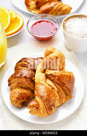 Le petit-déjeuner avec croissants, jus d'orange, confiture de framboises, café. Matin savoureux de nourriture. Banque D'Images