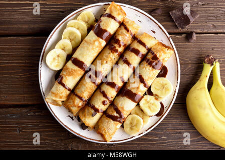 Délicieux rouleau crêpe avec des tranches de banane sur fond de bois. Haut de la vue, télévision lay Banque D'Images