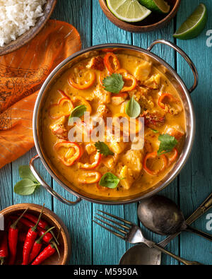 Un bol de délicieux curry rouge coco de style Thaï avec des poivrons, basilic, citron vert et coriandre. Banque D'Images