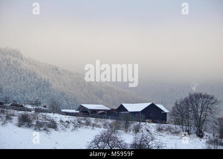 Rasa, Allemagne - Février 5th, 2018 - bâtiments de ferme sur une colline de neige avec des montagnes en arrière-plan Banque D'Images