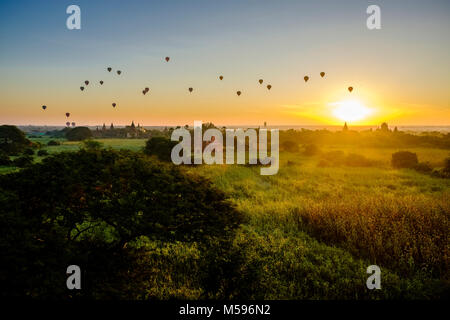 Les ballons à air chaud en survolant les pagodes de Bagan et les plaines brumeuses du site archéologique au lever du soleil Banque D'Images
