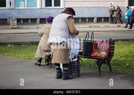 Vieille Femme ses sacs d'emballage sur le banc dans le parc Banque D'Images