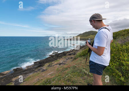 Un jeune homme à prendre des photos près de l'océan avec un appareil photo reflex analogique Banque D'Images