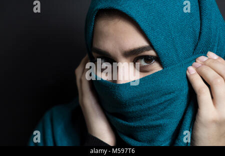 Belle jeune fille musulmane en hijab. Portrait d'une jeune femme arabe sur un fond noir. Banque D'Images