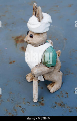 Ornement en bois d'un lapin habillé en chef standing sur une table de jardin en métal vintage Banque D'Images