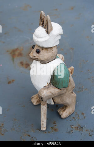Ornement en bois d'un lapin habillé en chef standing sur une table de jardin en métal vintage Banque D'Images