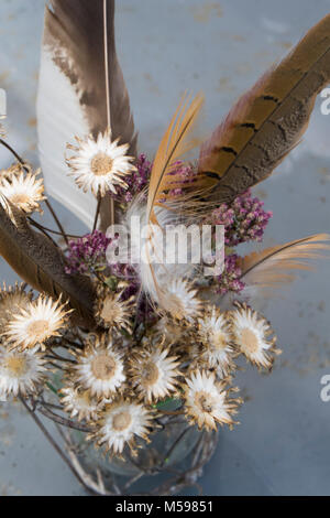 Des plumes et des fleurs séchées dans un vase en verre vintage et fils Banque D'Images