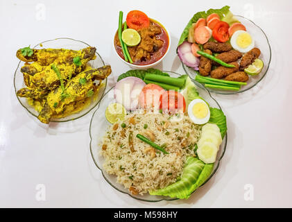 Bengali populaires indiens les plats avec du riz frit, les bâtonnets de poisson, mutton masala curry et tangra curry de poisson garni de salade. Banque D'Images