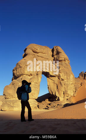 La Libye. Près de Ghat. Désert du Sahara. Akakus (Acacus) Parc National. Arche naturelle appelée Fezzenger. Femme, Tourisme photographiant arch. Banque D'Images