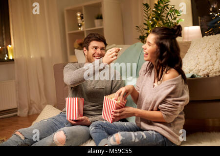Heureux couple eating popcorn at home Banque D'Images