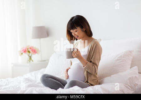 Happy pregnant woman with cup boire le thé à la maison Banque D'Images