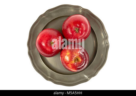 Mûres, trois pommes rouges sur une plaque de métal, de façon centralisée à partir de ci-dessus, sur un fond blanc Banque D'Images