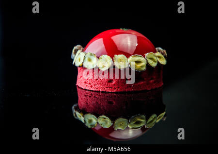 Musc rouge dessert décoré avec des bananes séchées et enduits de Mirror Glaze sur fond noir de côté Banque D'Images