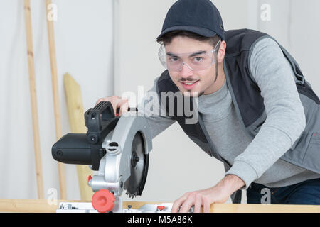 Jeune travailleur la coupe du métal bar avec scie circulaire Banque D'Images