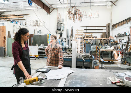 Deux femmes debout à workbench dans metal atelier. Banque D'Images