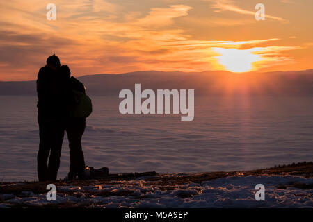 Couple sur la montagne couverte de neige Schoeckl à Graz sur la ville sous la montagne de stratus bas beau coucher du soleil à Koralpe Banque D'Images