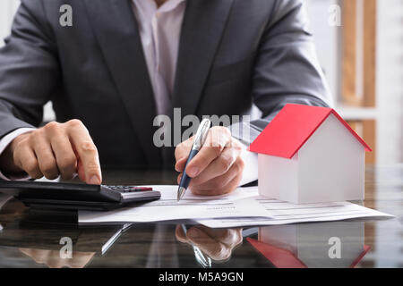 La main d'affaires Le calcul de facture avec House Model On Desk Banque D'Images