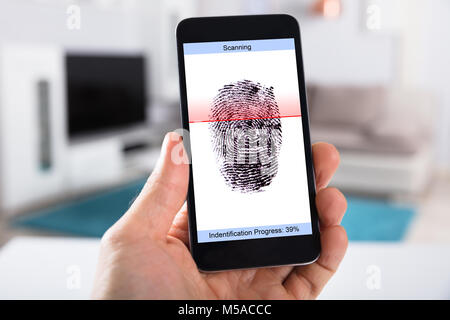 La main de personne avec un téléphone mobile montrant numérisation sur un écran d'empreintes digitales Banque D'Images