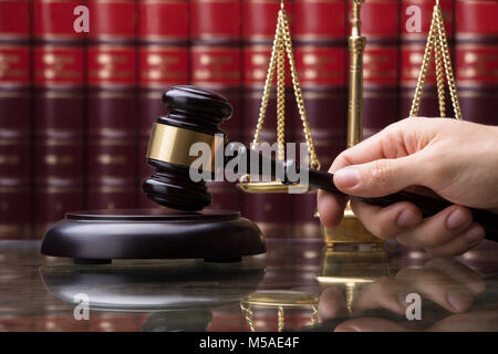 Close-up d'une main humaine Maillet frappant en face de l'échelle de pesage d'Or Banque D'Images