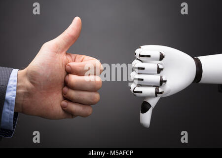 D'affaires et du Robot Showing Thumb Up et le pouce vers le bas signe sur fond gris Banque D'Images