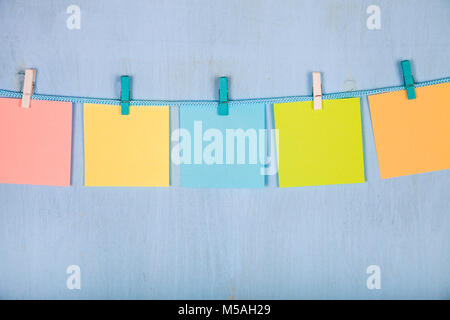 Cinq feuilles de papier accrocher sur une corde sur un fond en bois bleu. Banque D'Images