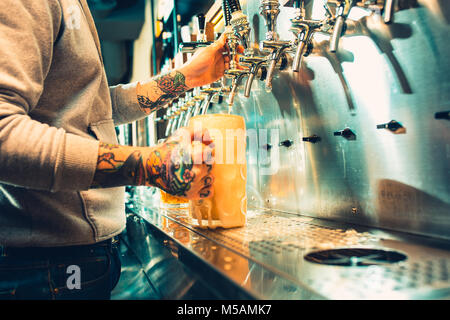 Main de bartender pouring une grande bière blonde au robinet. Banque D'Images