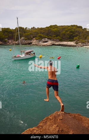 Jeune garçon sous des roches à Cala en Turqueta, Minorque, Iles Baléares, Espagne Banque D'Images