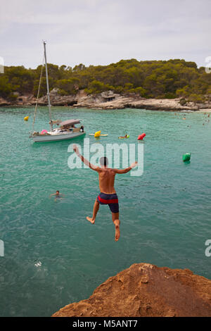 Jeune garçon sous des roches à Cala en Turqueta, Minorque, Iles Baléares, Espagne Banque D'Images