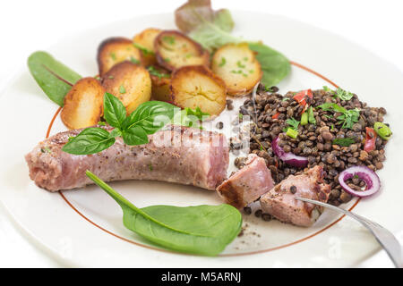 France La saucisse de Toulouse grillée avec potatoaes rôti et salade et lentilles sur fond blanc Banque D'Images