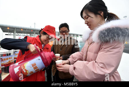 Yangzhou, Chine, province de Jiangsu. Feb 21, 2018. Un bénévole fournit l'eau chaude pour les passagers à la station de péage Shugang à Yangzhou, Chine de l'est de la province de Jiangsu, le 21 février 2018. L'augmentation des déplacements ont été assisté mercredi, le dernier jour de semaine de vacances du Nouvel An lunaire chinois, comme les gens à retourner au travail de leur ville natale. Credit : Zhuang Wenbin/Xinhua/Alamy Live News Banque D'Images